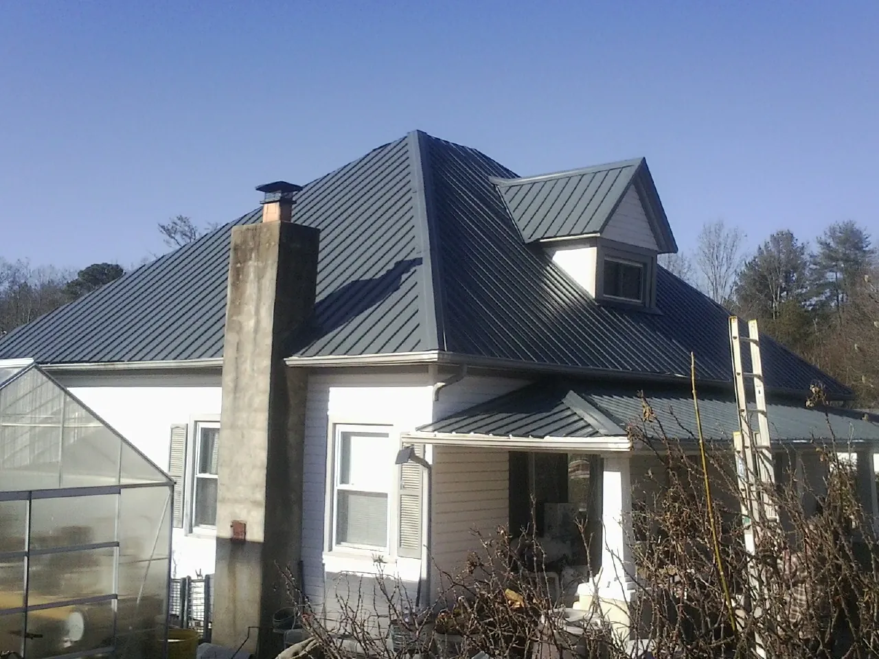 Dark blue standing seam metal roof on a white farmhouse with dormer — Slate & Tile Roof Repair by Roofing Brothers in Santa Barbara