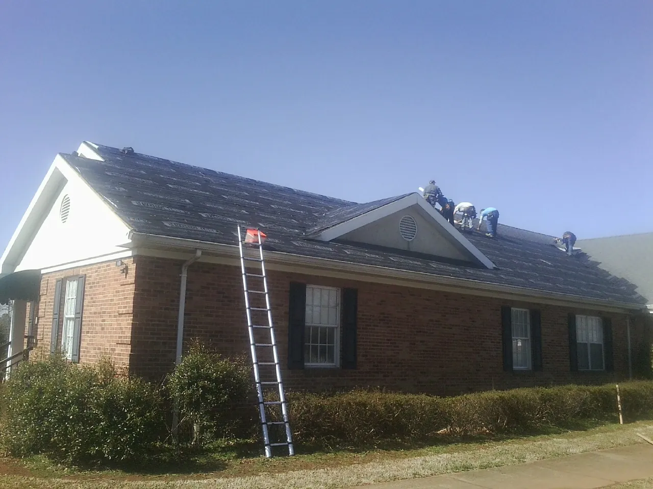 Crew tearing shingles off a brick ranch roof with a ladder set — Metal Roof Repair work by our crew in Santa Barbara