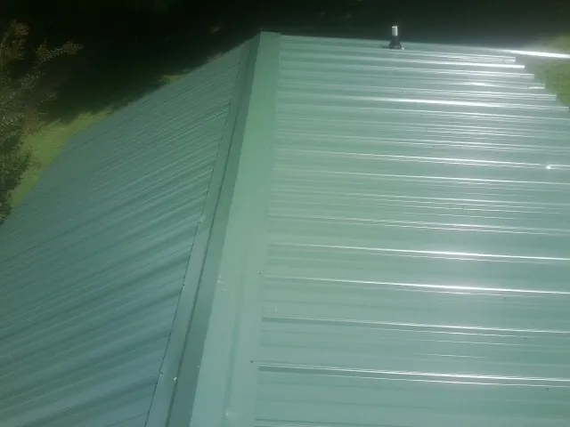 New green metal panels meeting at the ridge of a roof — Flat Roof Repair work by our crew in Santa Barbara
