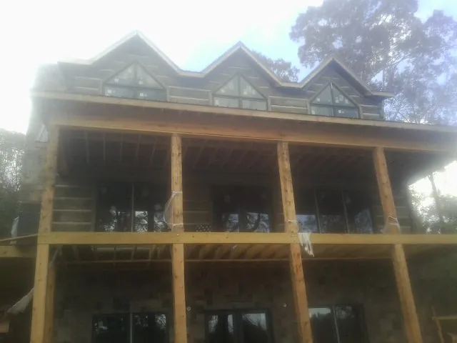 Dormers and porch framing on a large log home under construction — Roof Coating work by our crew in Santa Barbara