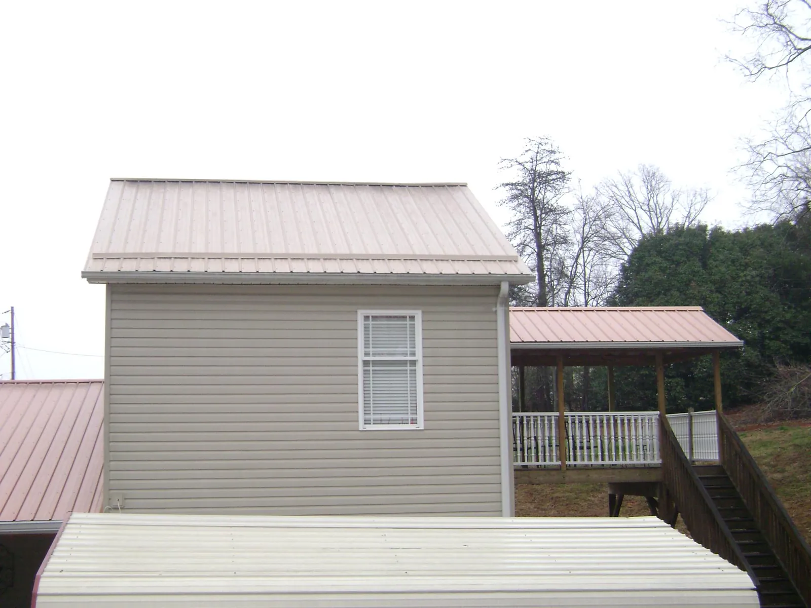 Tan metal roofs on a two story addition and attached porch, from a Roof Replacement job in Santa Barbara